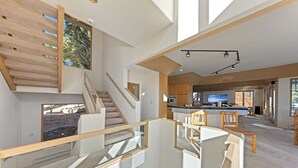 A modern interior with a staircase, a kitchen area, and a dining space. - 90s Tahoe Time Capsule (Incline Village)