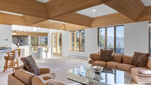 A spacious living area with a high ceiling, large windows, and a modern kitchen in the background. - 90s Tahoe Time Capsule (Incline Village)