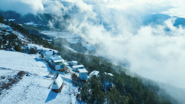 A snow-covered mountain village with modern buildings and a forested valley. - Shangri-La ManXinYu Frozen Dream Forest (Deqin)