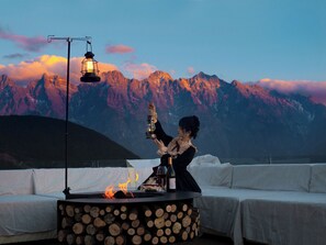 A person holding a lantern on a rooftop with a mountain backdrop. - Shangri-La ManXinYu Frozen Dream Forest (Deqin)