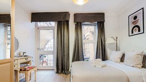 A hotel room with a bed, a desk, and a window with curtains.