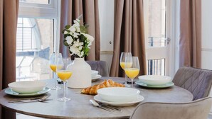 A breakfast table with plates, glasses, a vase of flowers, and croissants.