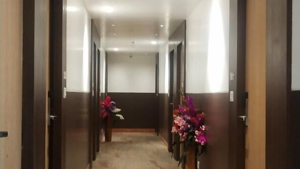 A long, well-lit hallway with dark wooden doors and marble flooring. - Amutham Residency (Tiruchirappalli)