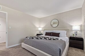A bedroom with a bed, two bedside tables, a round mirror, and a wall-mounted light fixture. - NEW|Heatherbrae 8|Old Town|Htd. Pool|Mtn View (Scottsdale)