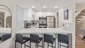 A modern kitchen with white cabinets, stainless steel appliances, and a central island with bar stools. - NEW|Heatherbrae 8|Old Town|Htd. Pool|Mtn View (Scottsdale)