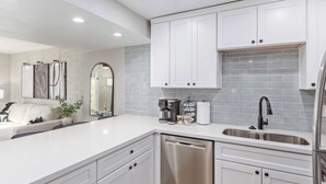 A modern kitchen with white cabinetry, a dishwasher, a sink, and a coffee maker. - NEW|Heatherbrae 8|Old Town|Htd. Pool|Mtn View (Scottsdale)