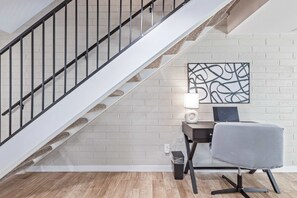 A staircase with a metal railing, a desk with a lamp, and a chair in a room with a brick wall and wooden flooring. - NEW|Heatherbrae 8|Old Town|Htd. Pool|Mtn View (Scottsdale)