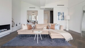 A modern living room with a beige sectional sofa, a round coffee table, and a fireplace. - 'Harbourview II' – Unmatched Views of the Iconic Opera House & Harbour Bridge! (Kirribilli)