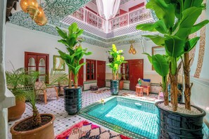 Amplio espacio interior con piscina, plantas en macetas y decoración tradicional.
