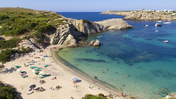 A beach with clear waters, rocky cliffs, and boats. - Castellsol 315 (Arenal d´en Castell)