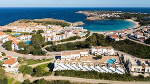 An aerial view of a coastal resort with multiple buildings, a beach, and a clear blue sea. - Castellsol 315 (Arenal d´en Castell)