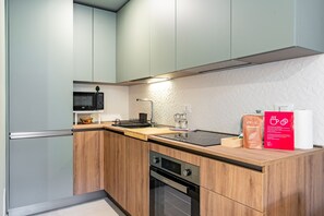 Une cuisine moderne avec des meubles de couleur bois clair, un micro-ondes noir, un four encastré et une machine à café.