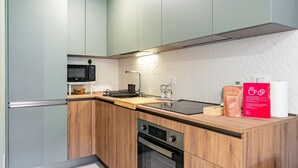 Une cuisine moderne avec des meubles de couleur bois clair, un micro-ondes noir, un four encastré et une machine à café.