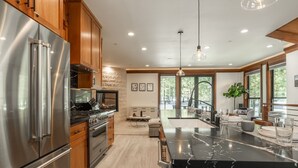A modern kitchen with stainless steel appliances, wooden cabinets, a marble countertop, and a large island. - Private Hot Tub | Near Eagle Lodge (Mammoth Lakes)
