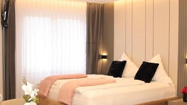 A modern hotel room with a large bed, a bedside table, and a nightstand.