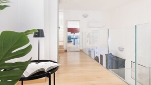 A modern interior with a wooden floor, a glass partition, and a visible kitchen area in the background. - Easylife - Modern Comfort in Porta Venezia (Milano)