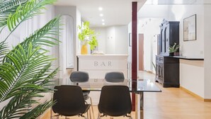 A modern kitchen with a bar area, featuring a glass table and chairs, and a large potted plant. - Easylife - Modern Comfort in Porta Venezia (Milano)