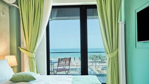 A hotel room with a bed, a chair, a view of the beach, and a window with curtains. - HOTEL AZALEEA MAMAIA NORD (Navodari)