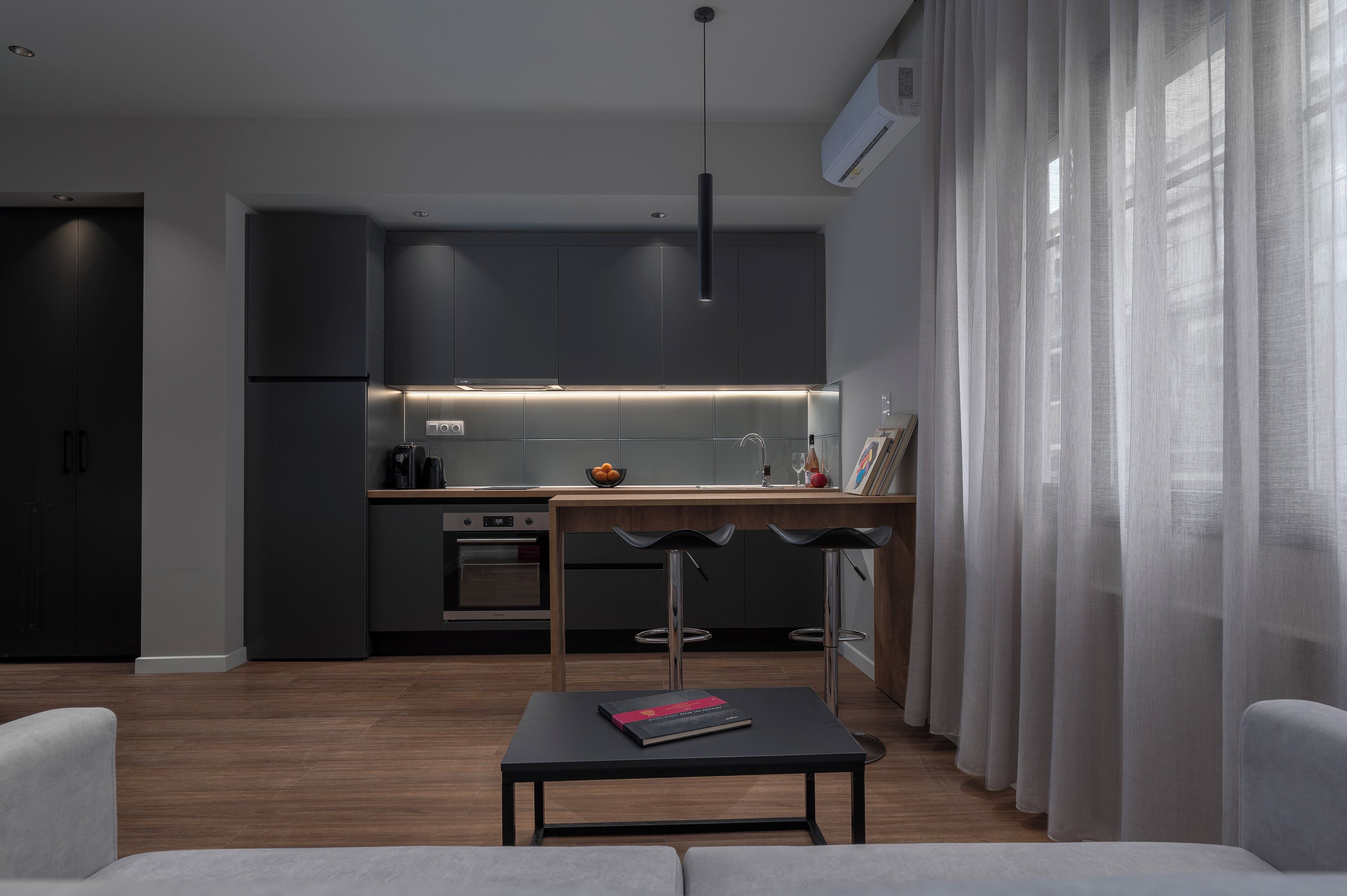 A modern kitchen with dark cabinetry, a central island, and pendant lighting.