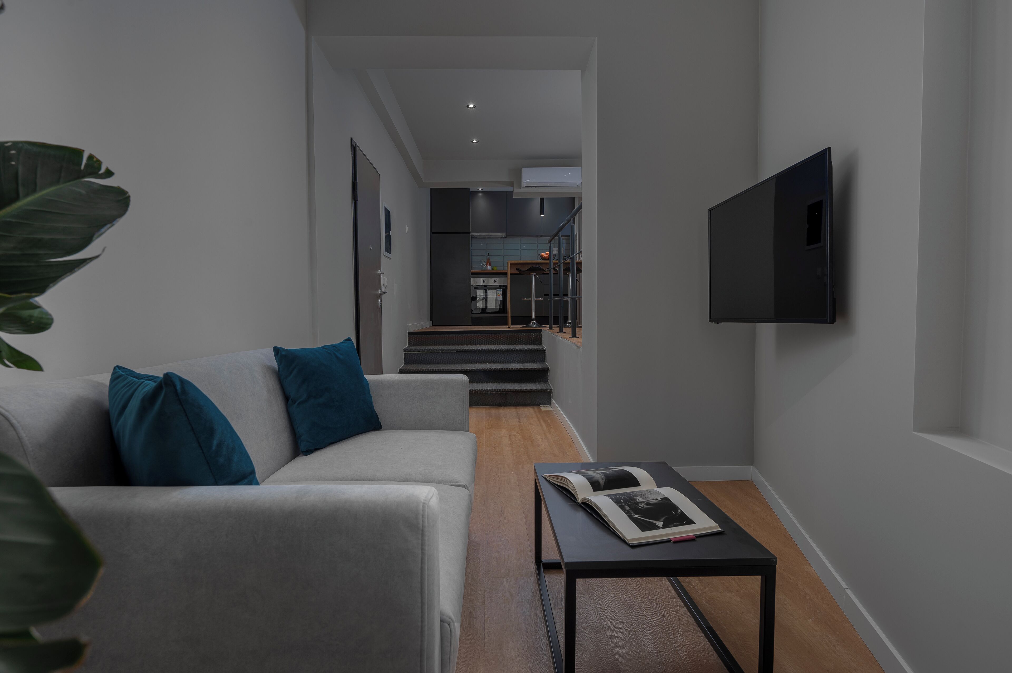 A modern living room with a sofa, coffee table, and a flat-screen TV mounted on the wall.