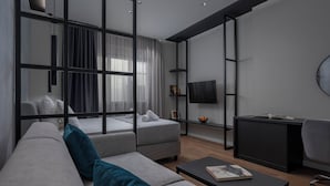 A modern living room with a sofa, a coffee table, a TV, and a desk. - Hebrard Industrial Suites (Thessaloniki)
