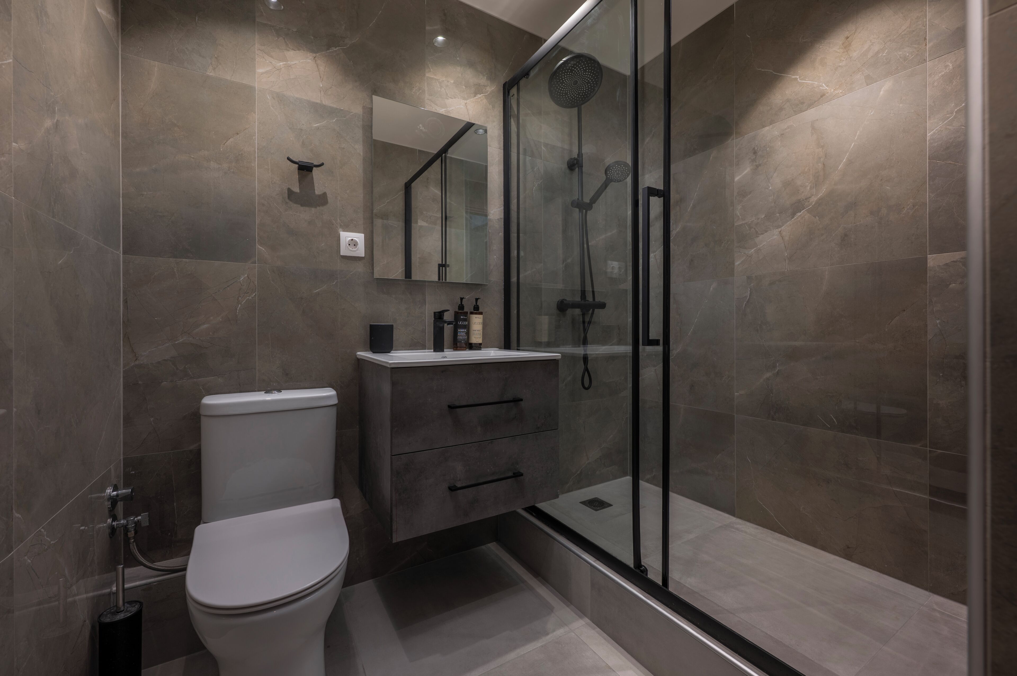 A modern bathroom with a toilet, vanity, and a glass-enclosed shower area.