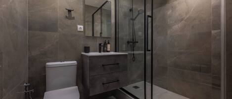 A modern bathroom with a toilet, vanity, and a glass-enclosed shower area.
