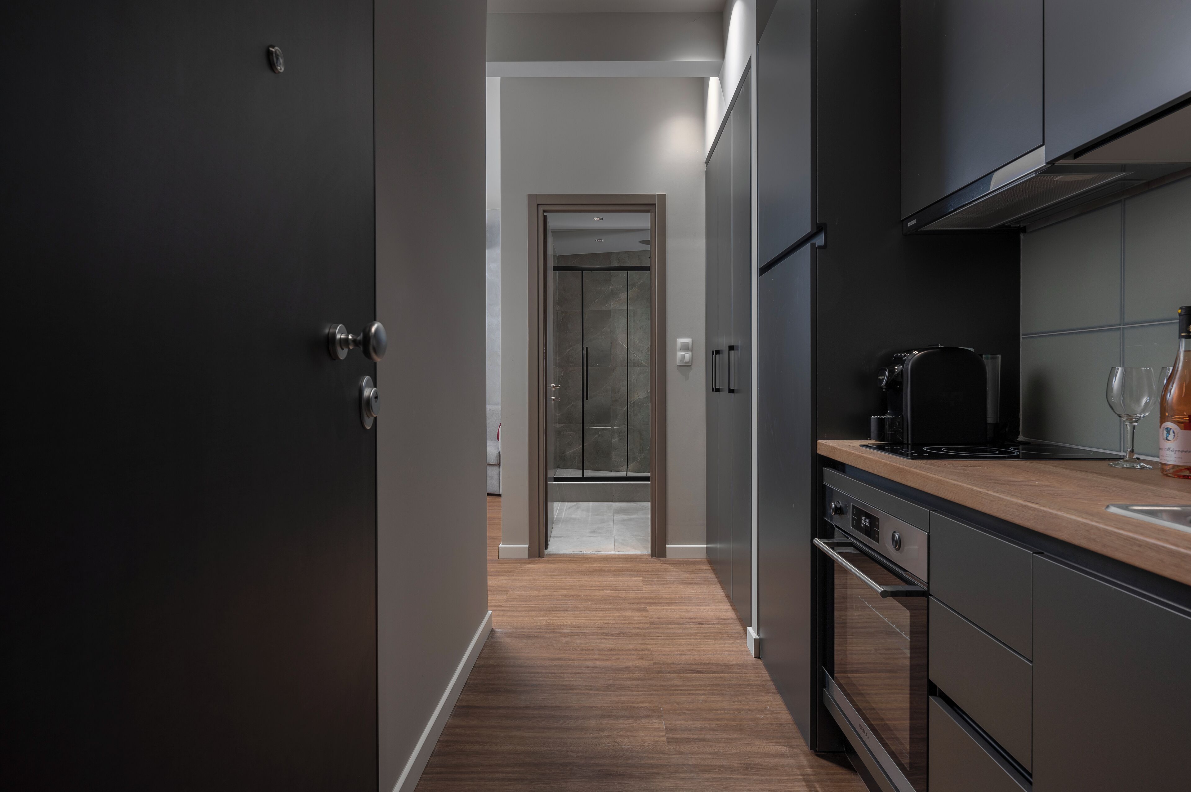 Una cucina moderna con mobili scuri, un piano di lavoro in legno e un forno integrato.