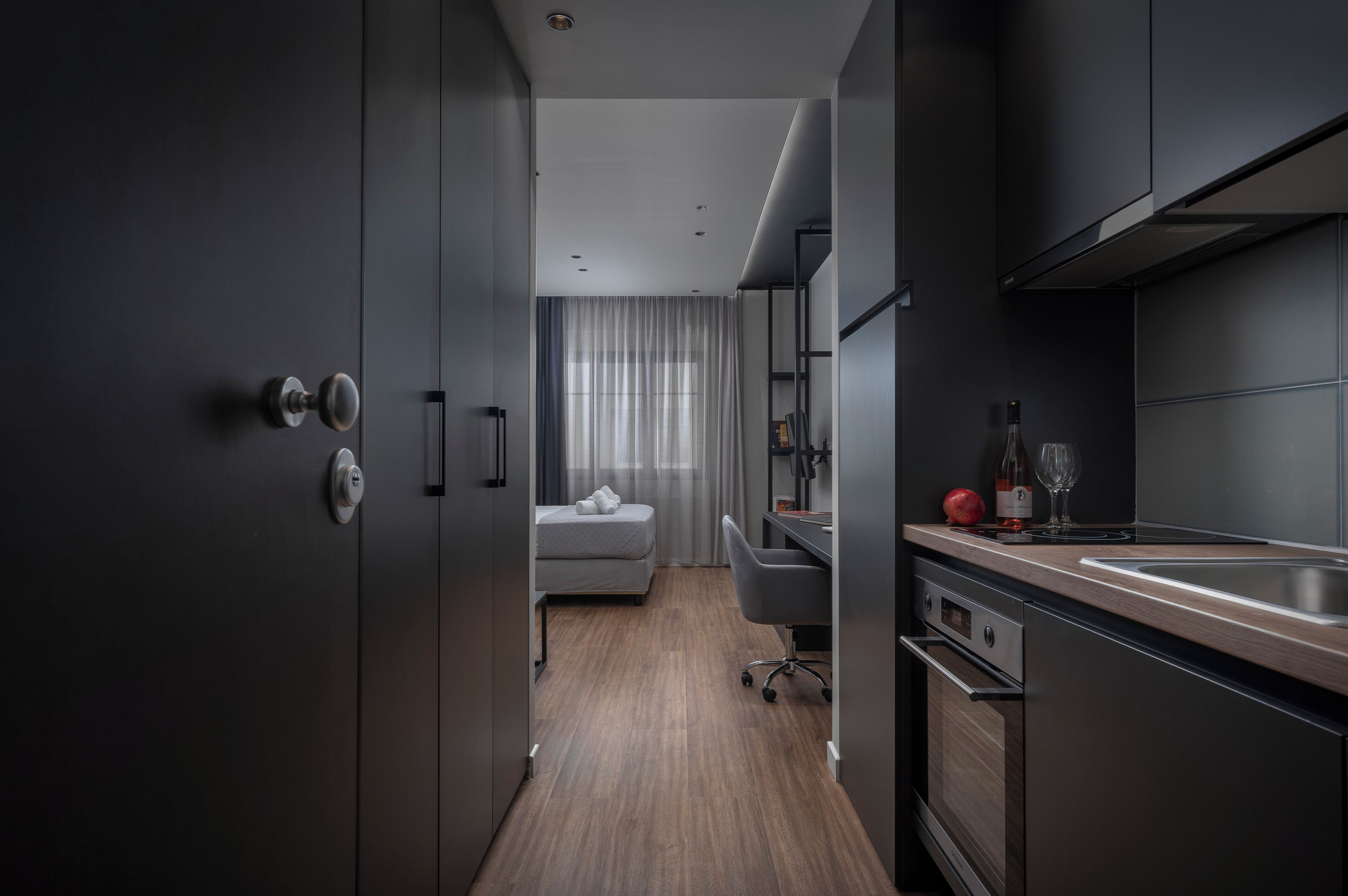 Une cuisine moderne avec des meubles de couleur sombre, un plan de travail en bois et un four encastré.