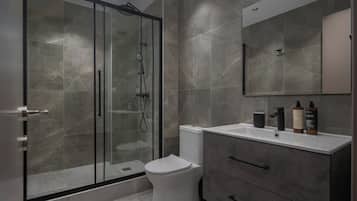 A modern bathroom with a glass-enclosed shower, a white toilet, and a vanity with a mirror and toiletries.