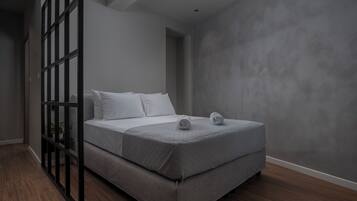 A modern bedroom with a bed, a black metal partition, and a grey textured wall.