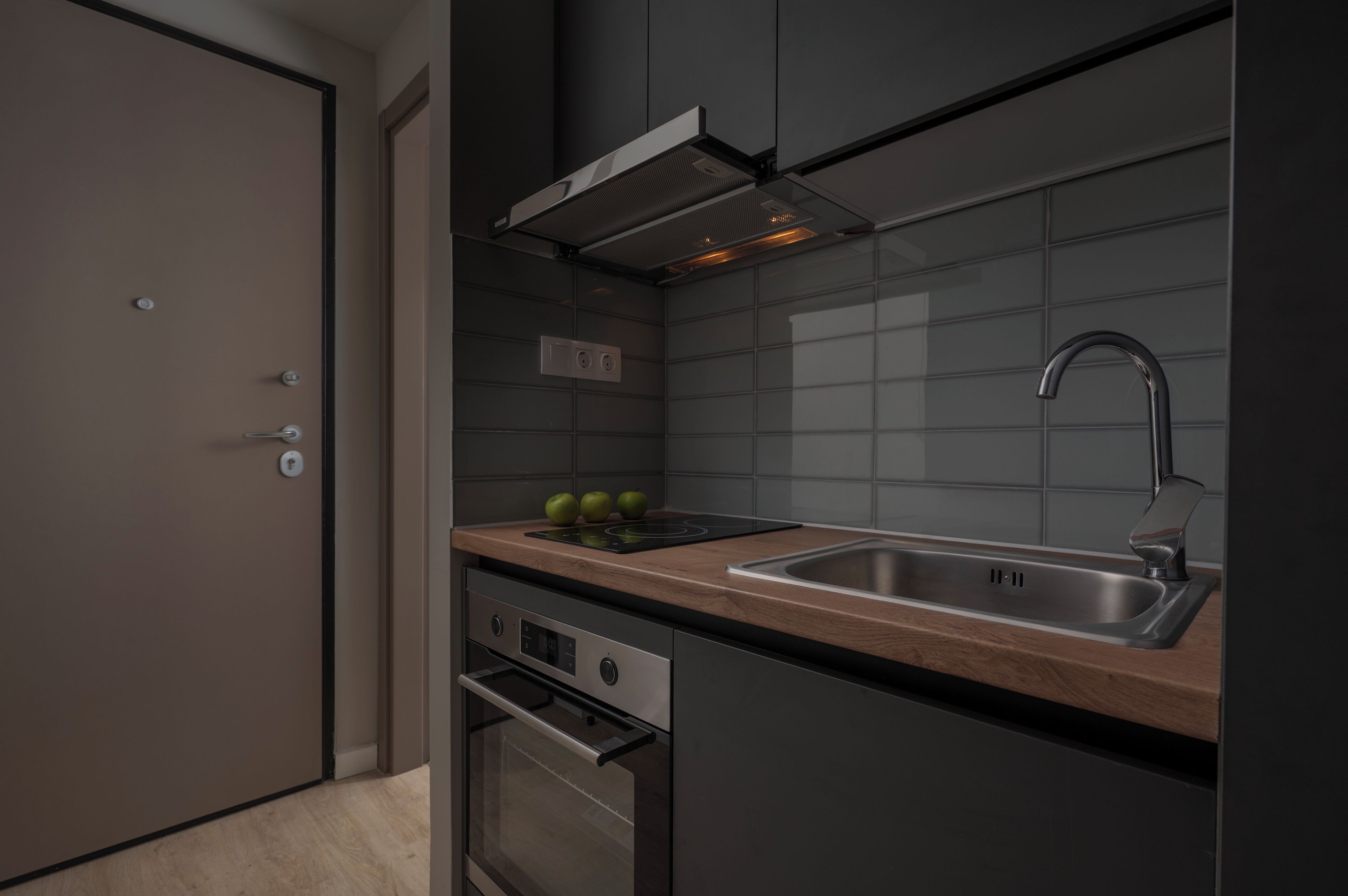 Una cocina moderna con un lavamanos de acero inoxidable, horno integrado y encimera de madera.