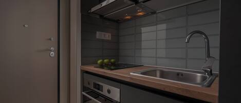 Una cocina moderna con un lavamanos de acero inoxidable, horno integrado y encimera de madera.
