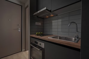 A modern kitchen with a stainless steel sink, a built-in oven, and a wooden countertop. - Hebrard Industrial Suites (Thessaloniki)