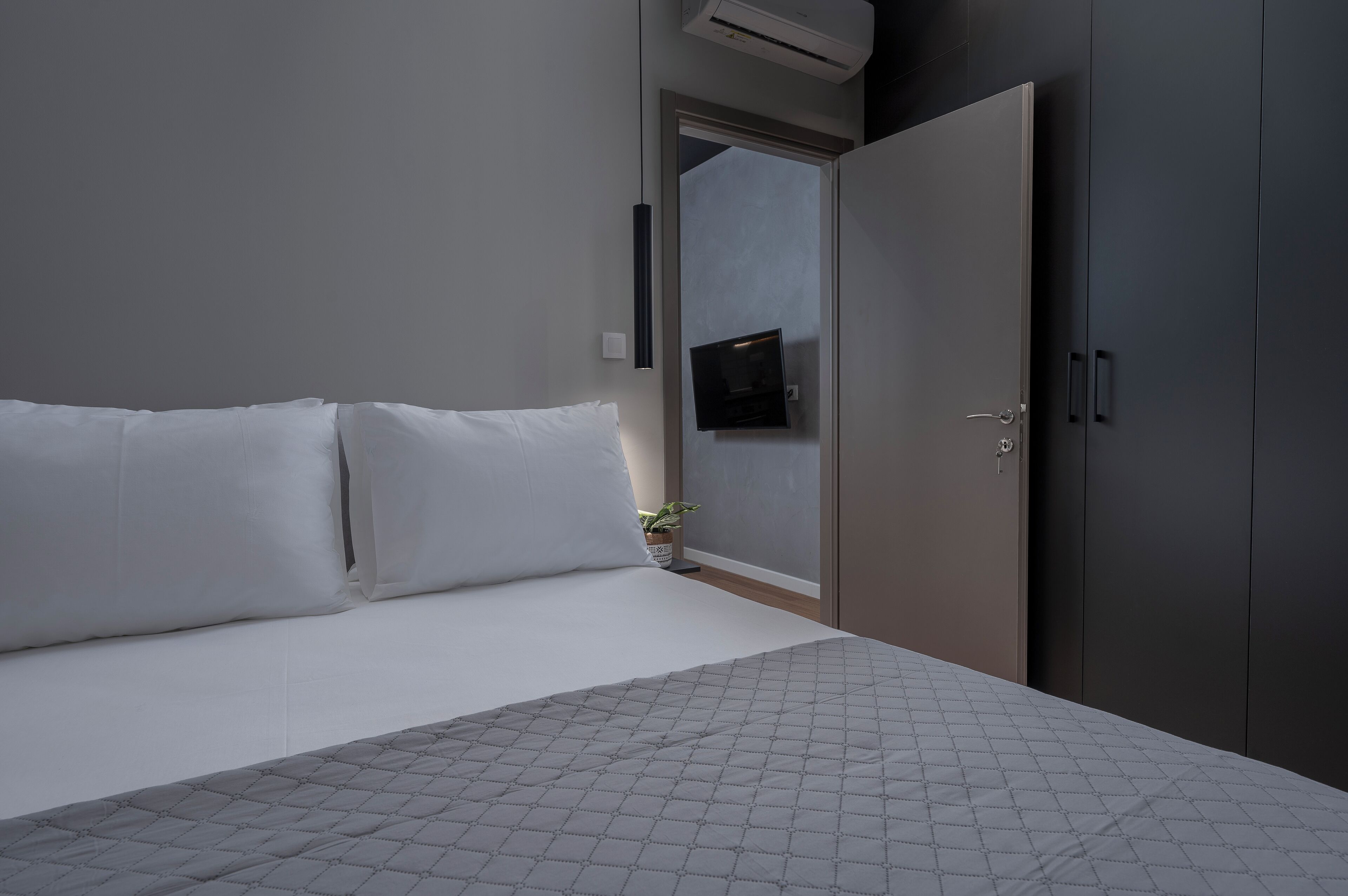 Un dormitorio moderno con cama, armario y televisor de pared.