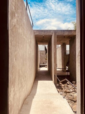 A narrow concrete corridor with a staircase leading to an open area. - Aleela Villa (Chiang Mai)