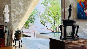 Una habitación con un ventanal grande, una estatua, un cuadro y una mesa de madera.