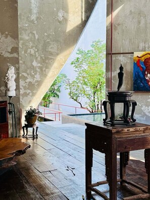 A room with a large window, a statue, a painting, and a wooden table. - Aleela Villa (Chiang Mai)