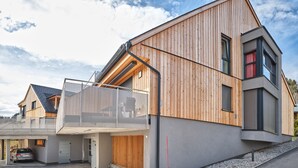 A modern two-story house with a wooden facade, a covered driveway, and a car parked inside. - The Mountain Suite Top  11 - Tauplitz Residences (Tauplitz)