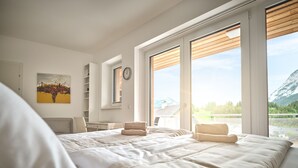 A bedroom with a large bed, a desk, a chair, and a view of a mountain. - The Mountain Suite Top  11 - Tauplitz Residences (Tauplitz)