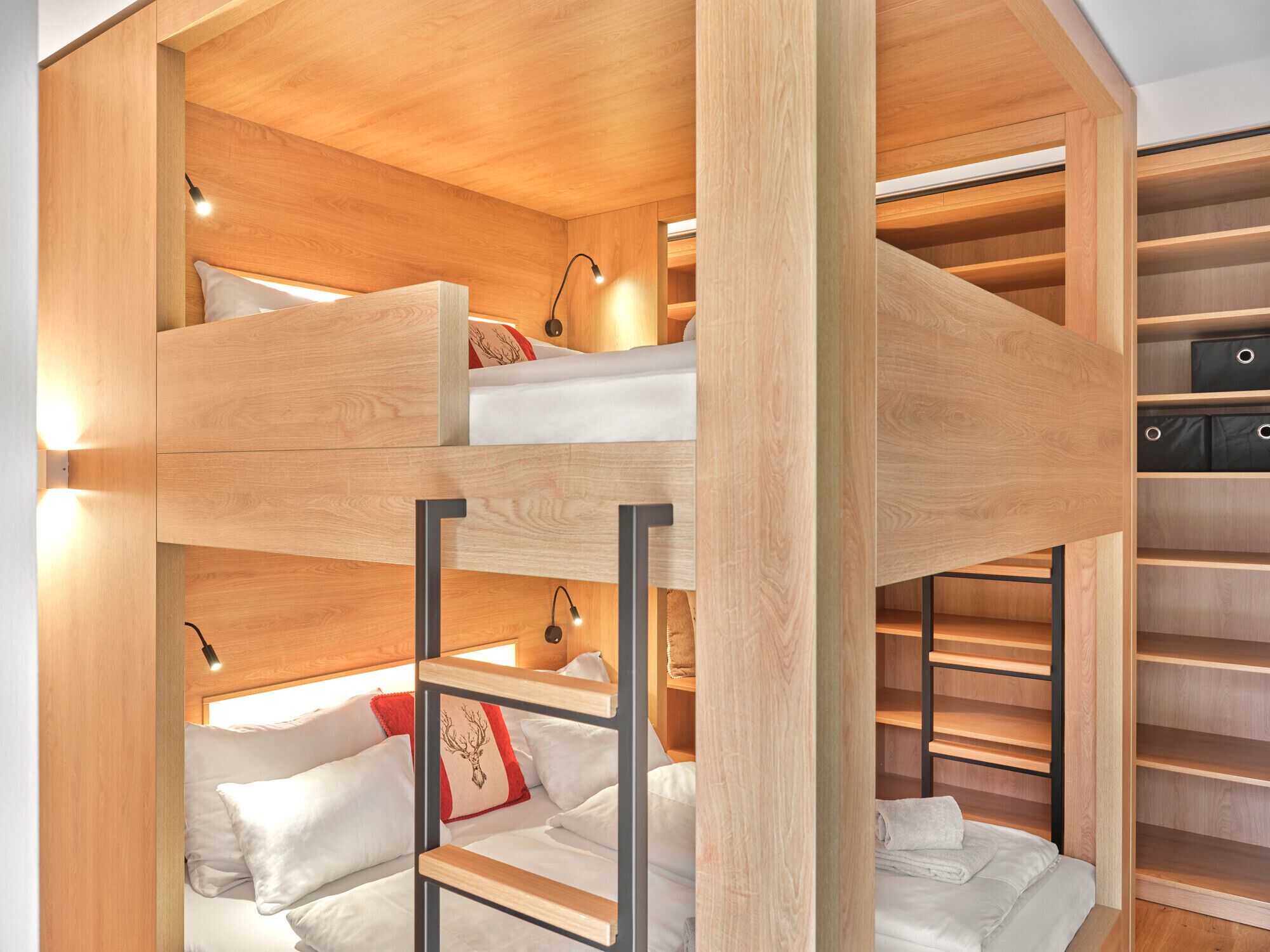 A bunk bed room with built-in shelving and lighting.