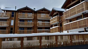 Un bâtiment en bois à plusieurs étages, doté de balcons, et entouré de neige.