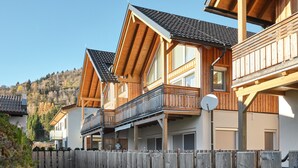 Una fila di case di legno con balconi, un vialetto sterrato e una recinzione in legno.