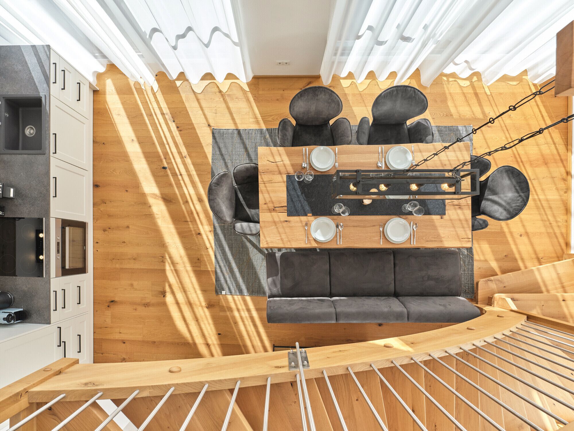Una habitación moderna con techo de madera, un sofá y una mesa de comedor preparada para cuatro.