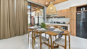 Una cocina moderna con armarios de madera, un refrigerador de acero inoxidable y un comedor con mesa dispuesta para cuatro personas.