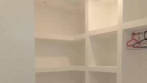 Une pièce blanche et vide, avec un sol carrelé et un mur blanc.