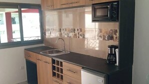 Une cuisine moderne avec des meubles en bois, un évier en acier inoxydable, un four à micro-ondes et une machine à café.