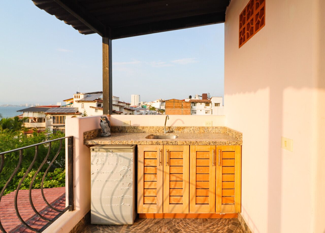 Ein Balkon mit Spüle, Holzsäcken und Blick auf die Stadt.