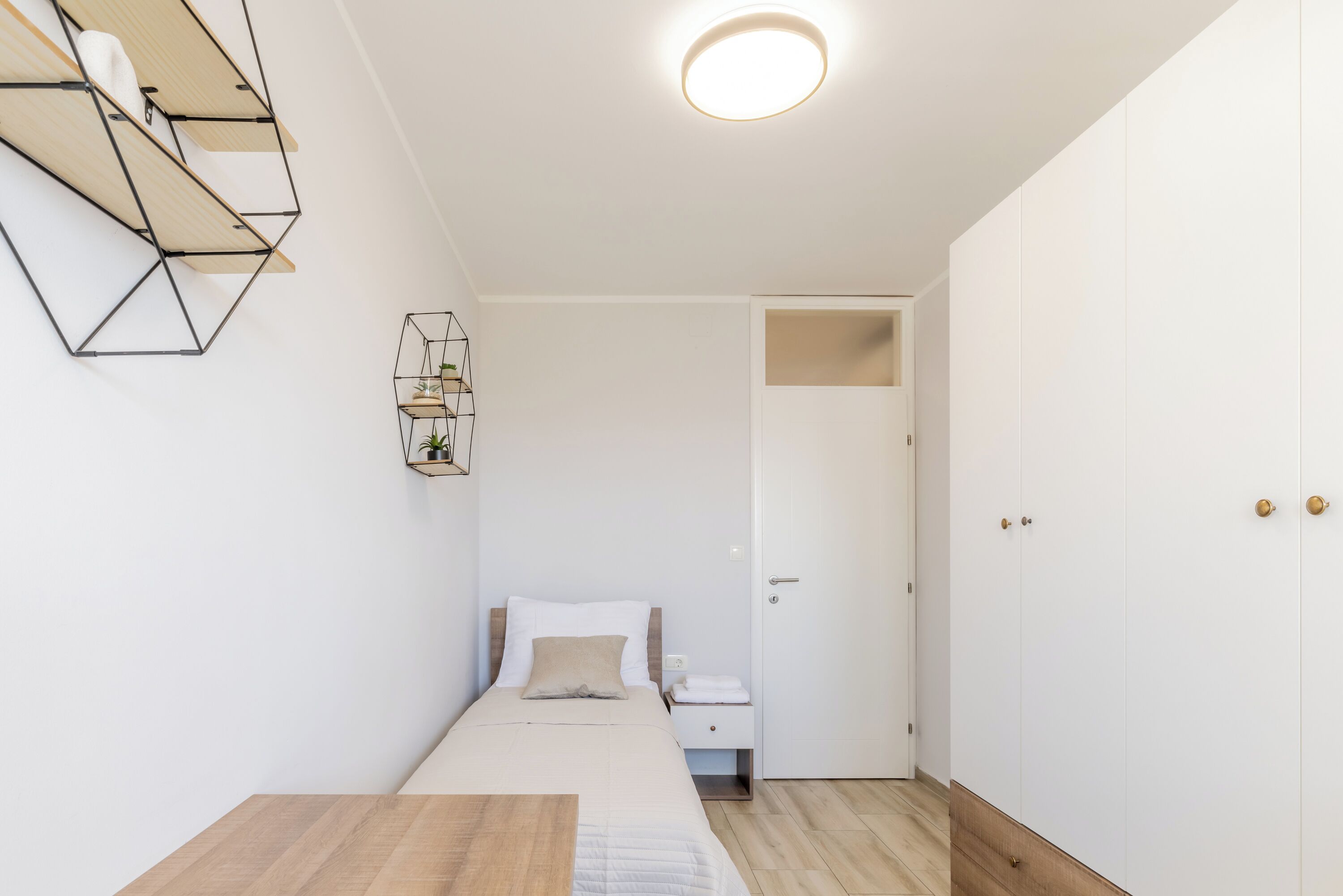 A minimalist bedroom with a bed, bedside table, and a wardrobe.