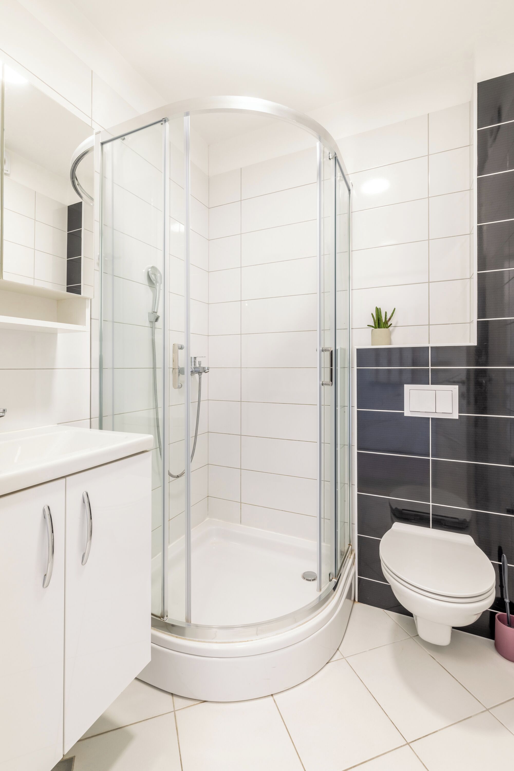 A modern bathroom with a glass-enclosed shower, a white toilet, and a white sink with a cabinet.